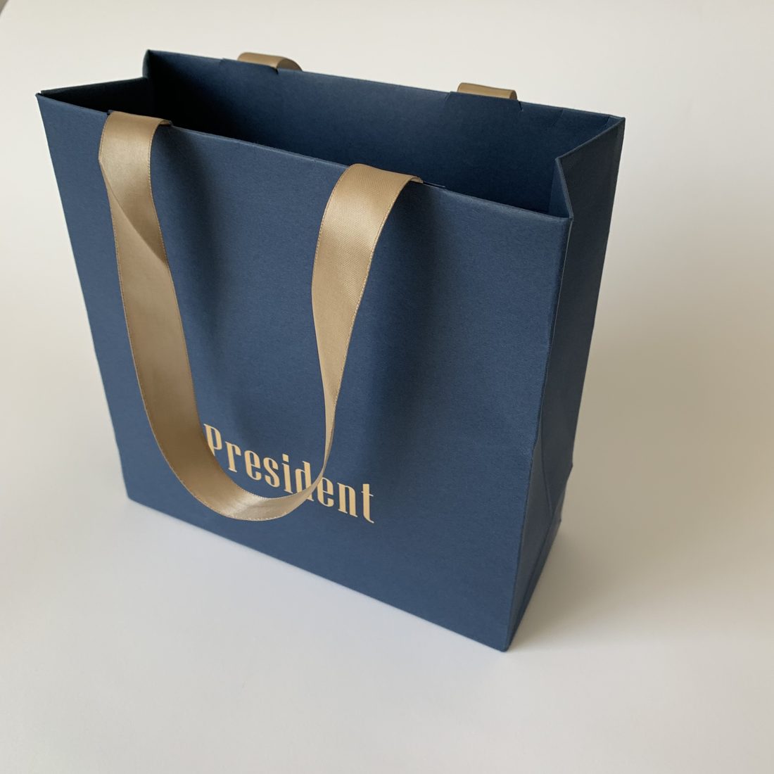Kraft and black paper shopping bags with twisted handles on a stone surface