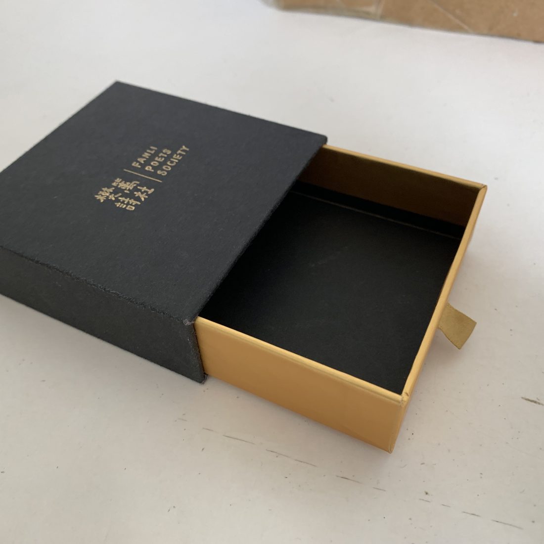 Burgundy sliding drawer box open with gold foil logo and two glass bottles in an insert