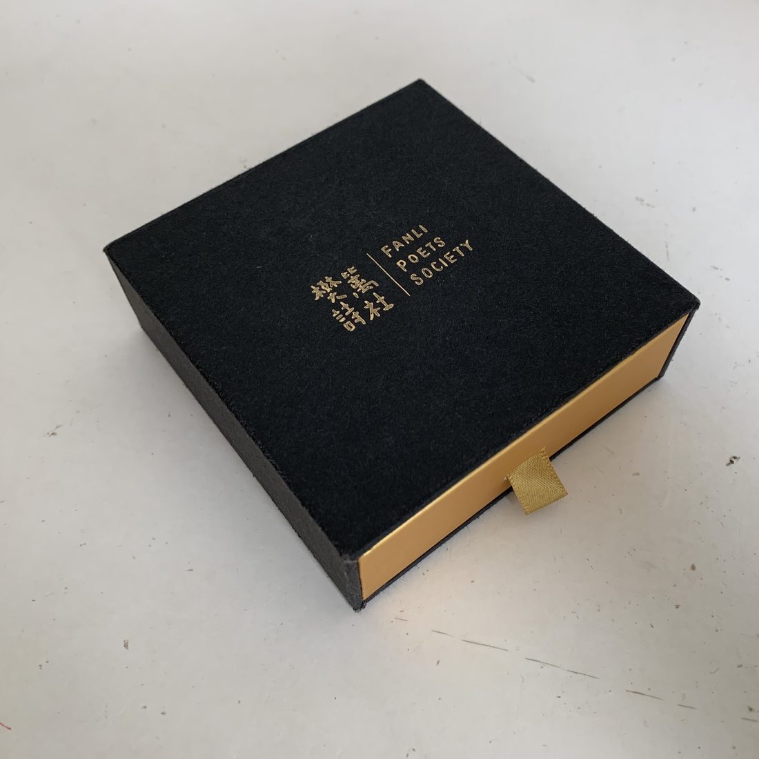 Charcoal rigid lid-and-base gift box open with ribbon, next to a sage green box
